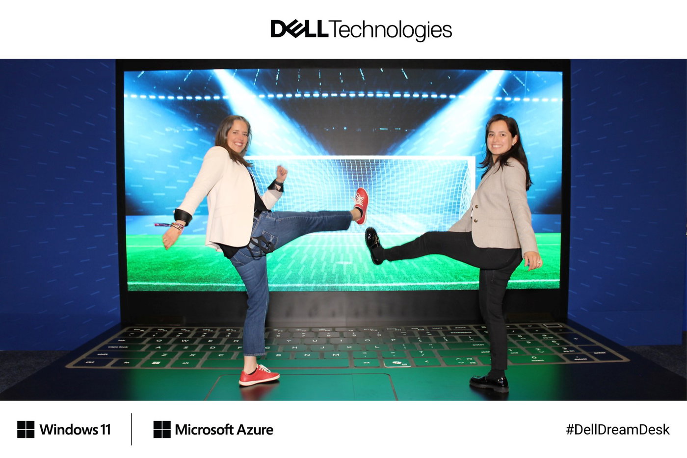 Two guests kicking a pretend ball on the giant laptop with a stadium on its screen