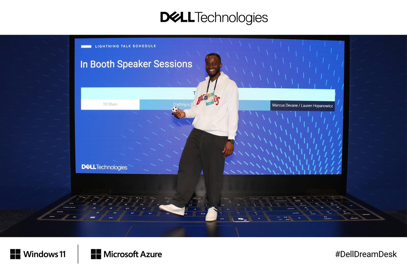 A guest on the giant laptop in front of the booth's speaker session schedule