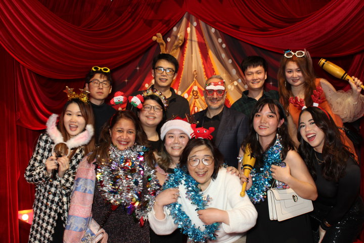 PwC colleagues in Santa hats and tinsel at their holiday party photo booth