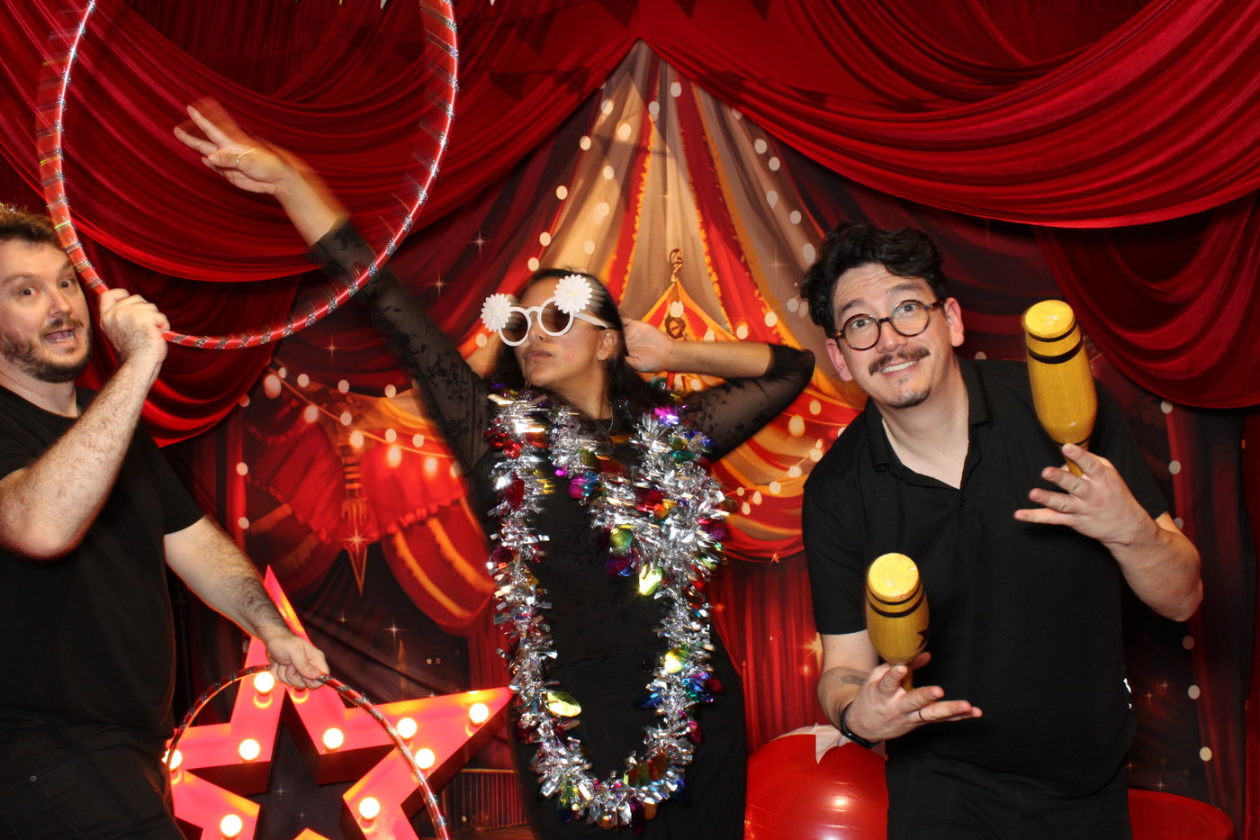 PwC colleagues with a hula hoop, tinsel and juggling pins in front of a circus big-top scene