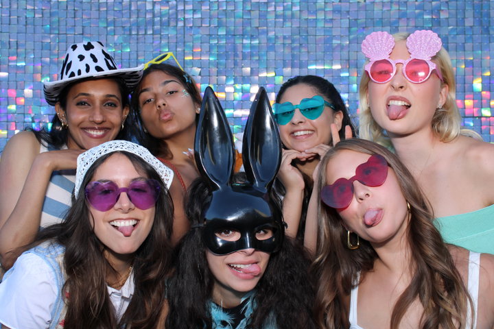 Friends in party glasses and a bunny mask on a holographic shimmer wall
