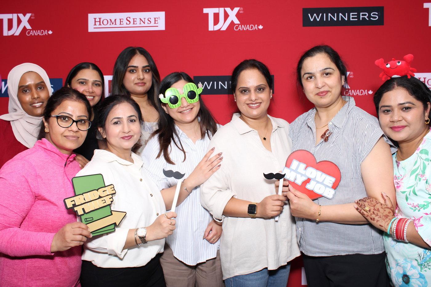 New TJX Canada team members with heart and sign props at the photo booth